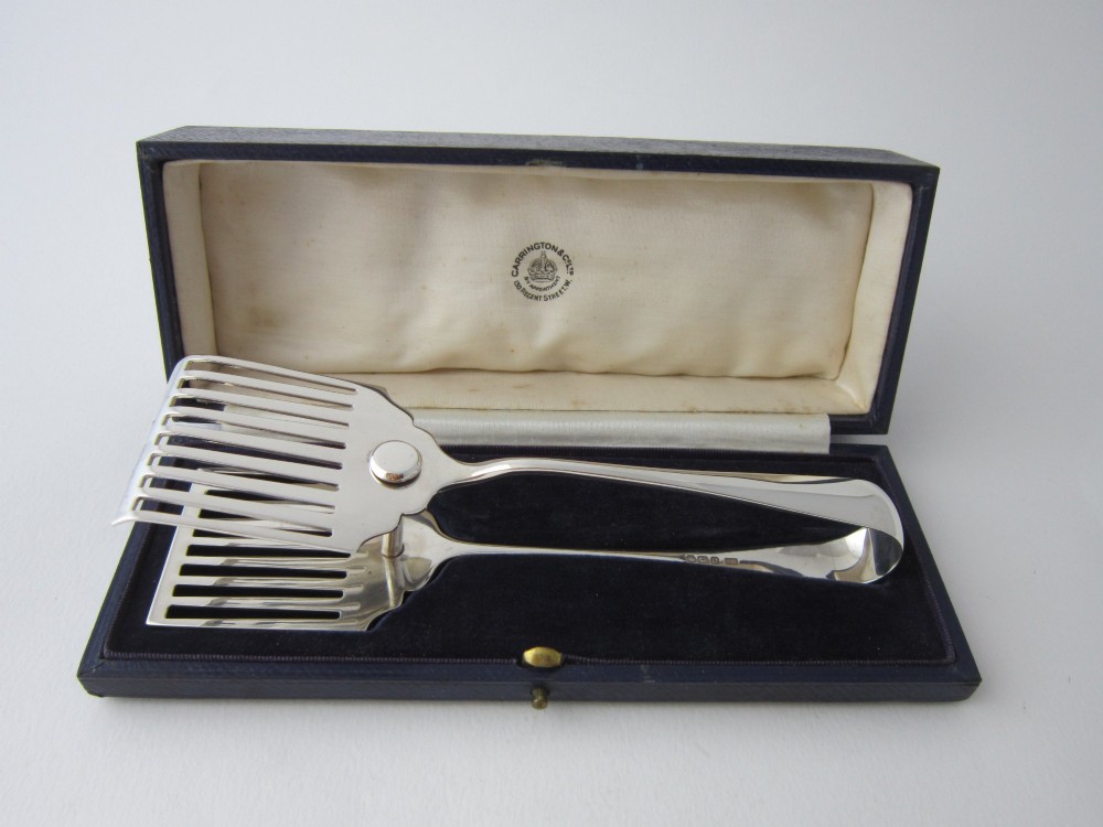 A pair of hallmarked sterling silver asparagus serving tongs with slotted blades resting inside a fitted presentation case.