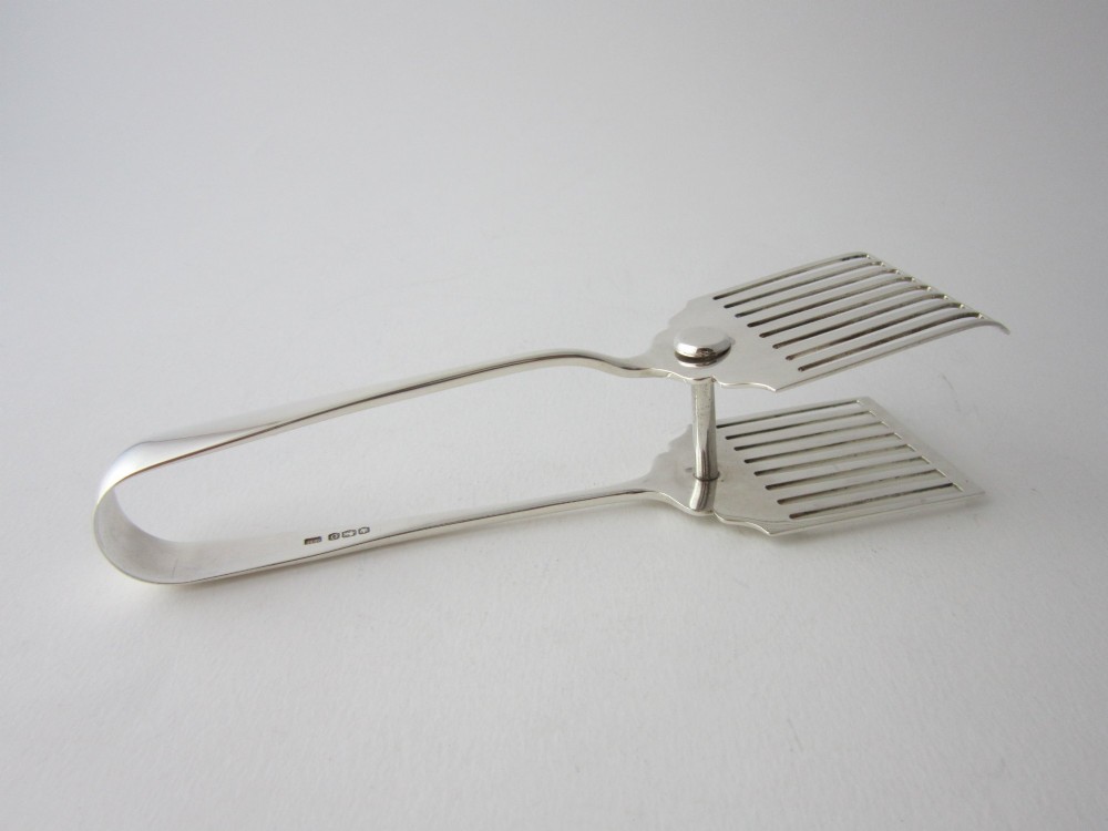 A pair of hallmarked sterling silver asparagus serving tongs with slotted blades resting inside a fitted presentation case. View IV