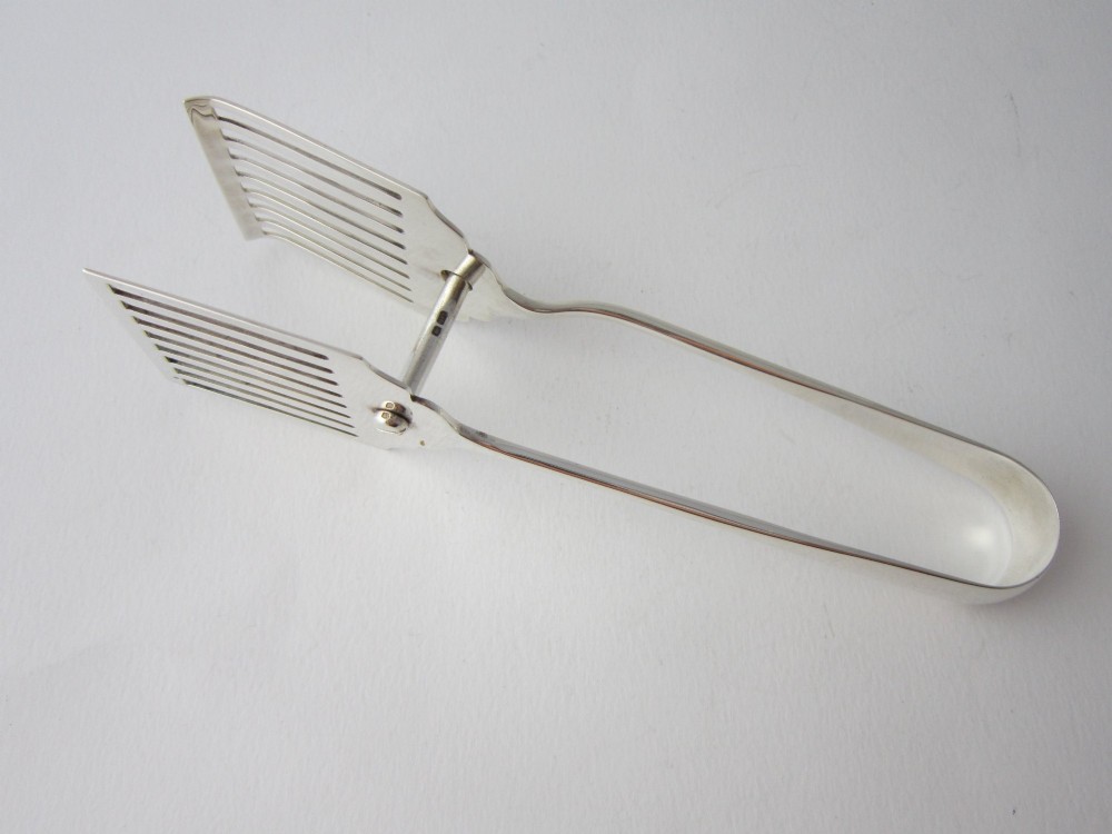 A pair of hallmarked sterling silver asparagus serving tongs with slotted blades resting inside a fitted presentation case. View V