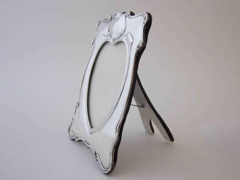 An Edwardian sterling silver photograph frame featuring sinuous Art Nouveau scrolls, a heart-shaped central aperture, and visible British hallmarks. View III