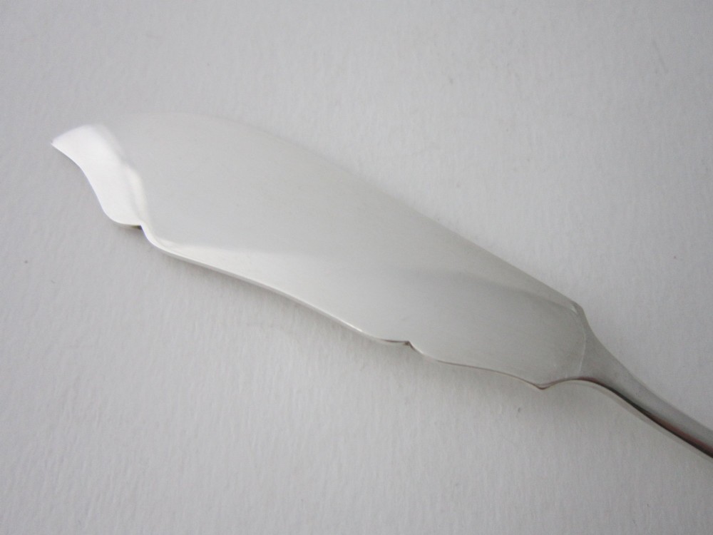 An Edwardian sterling silver butter knife with engraved scrollwork and foliate details on the blade and handle. View V