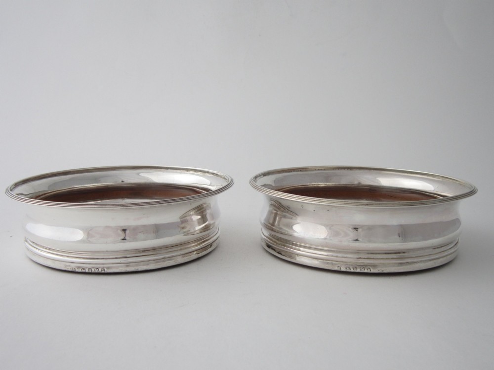 A pair of circular George III sterling silver wine coasters featuring turned wooden bases with central silver bosses and plain silver rims. View II