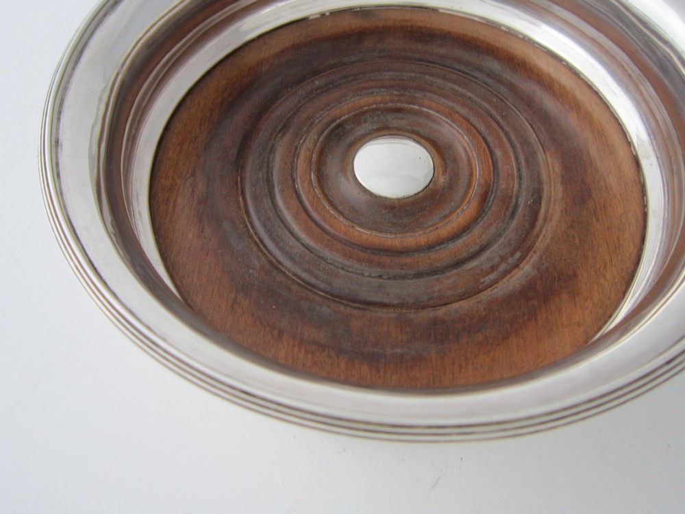 A pair of circular George III sterling silver wine coasters featuring turned wooden bases with central silver bosses and plain silver rims. View IV