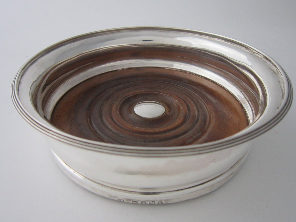 A pair of circular George III sterling silver wine coasters featuring turned wooden bases with central silver bosses and plain silver rims. View V