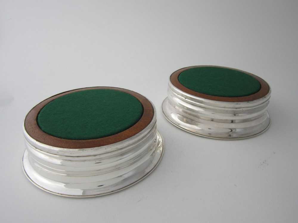 A pair of circular George III sterling silver wine coasters featuring turned wooden bases with central silver bosses and plain silver rims. View VII