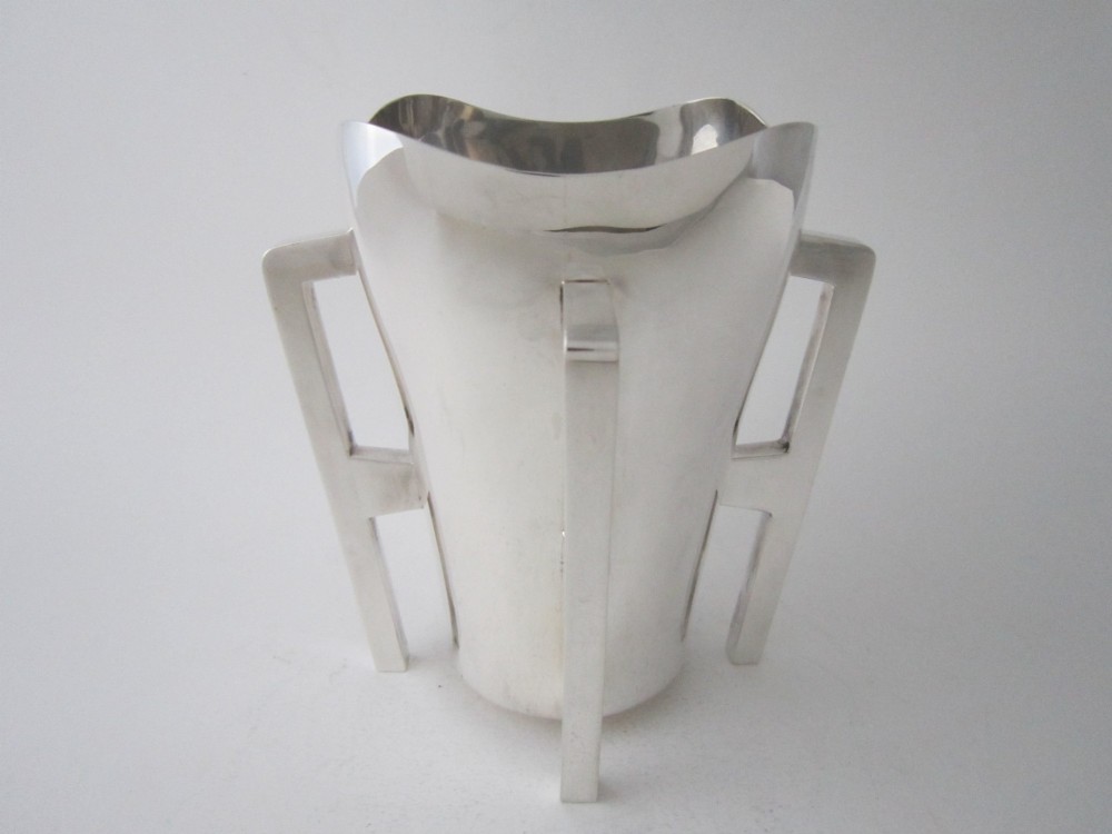 An Edwardian sterling silver mether cup featuring a square mouth and four angular handles that extend downward to form the feet.