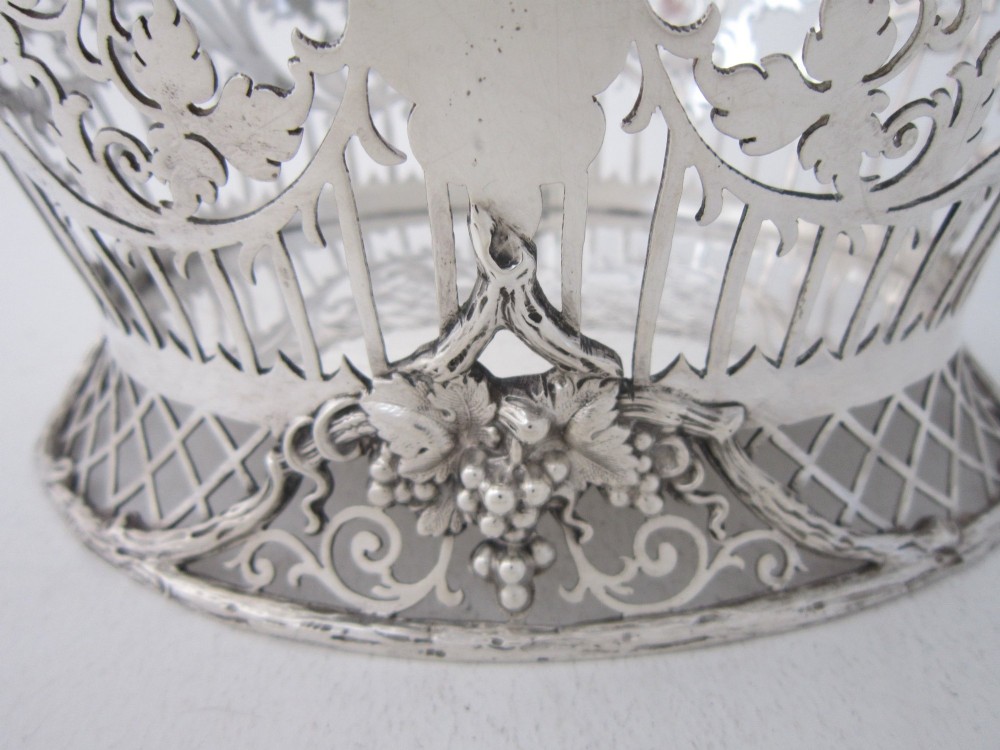 An antique George V sterling silver basket featuring intricate pierced lattice metalwork, scrolled grapevine borders, and visible hallmarks. View VII