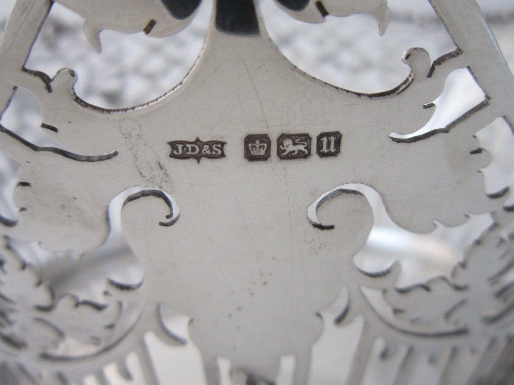 An antique George V sterling silver basket featuring intricate pierced lattice metalwork, scrolled grapevine borders, and visible hallmarks. View XI