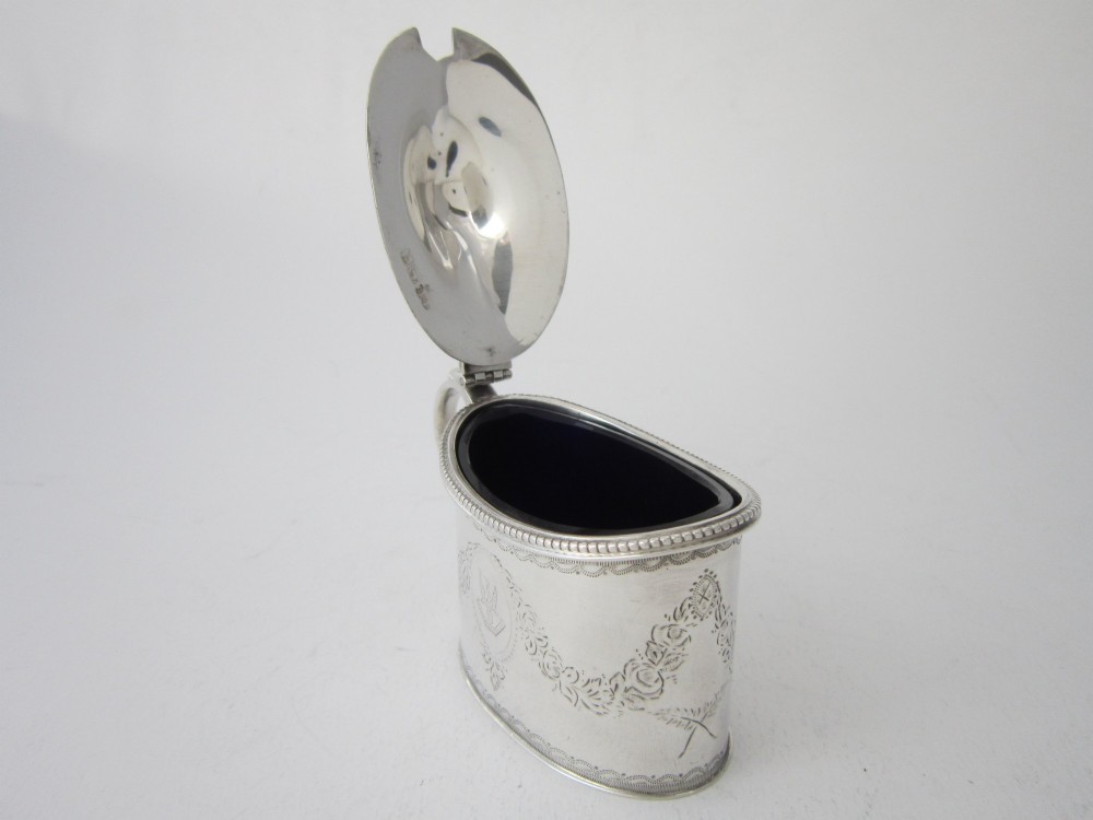 An oval sterling silver mustard pot featuring bright-cut engraved patterns, a beaded rim, a scroll handle, and a matching spoon. View VII