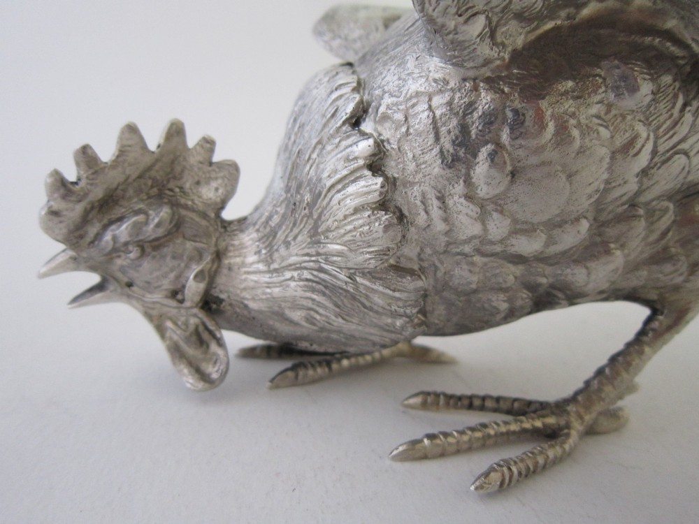 A pair of detailed sterling silver figures depicting fighting cockerels with open wings and realistic feather textures. View IV