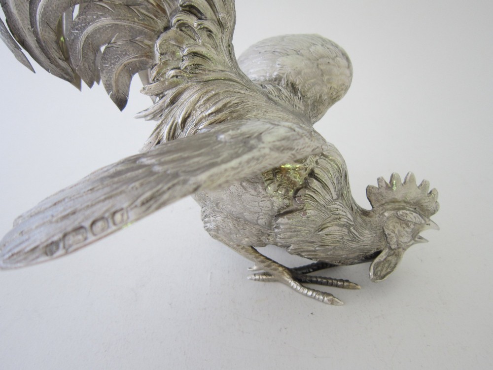 A pair of detailed sterling silver figures depicting fighting cockerels with open wings and realistic feather textures. View VI