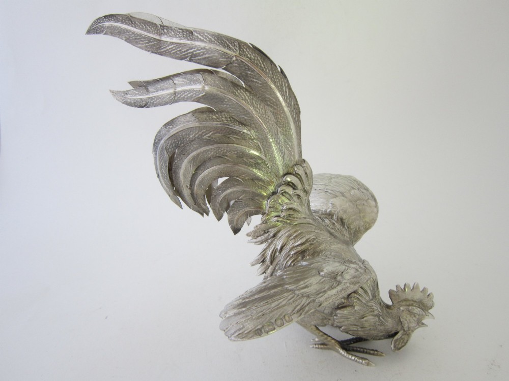 A pair of detailed sterling silver figures depicting fighting cockerels with open wings and realistic feather textures. View VII