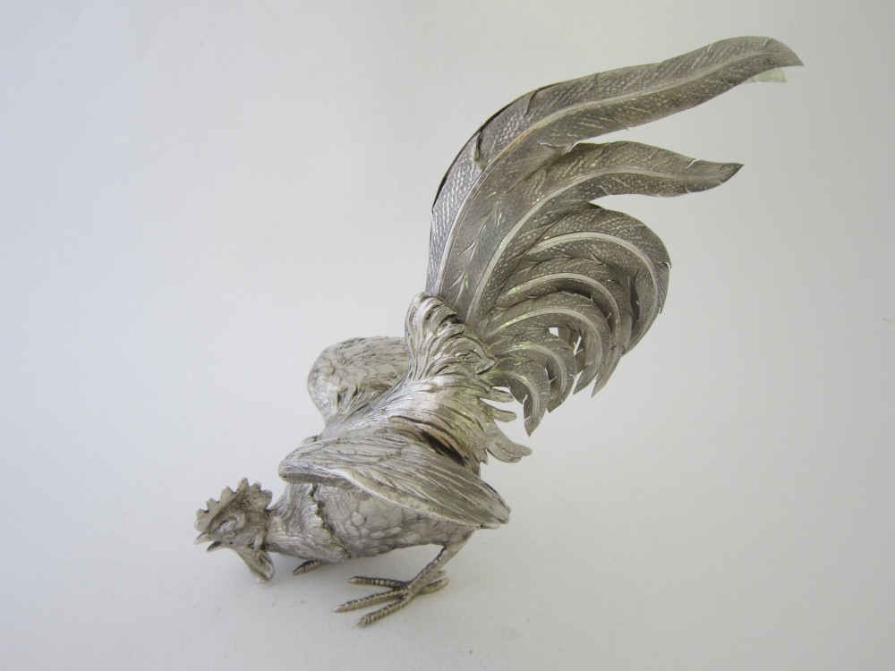 A pair of detailed sterling silver figures depicting fighting cockerels with open wings and realistic feather textures. View VIII