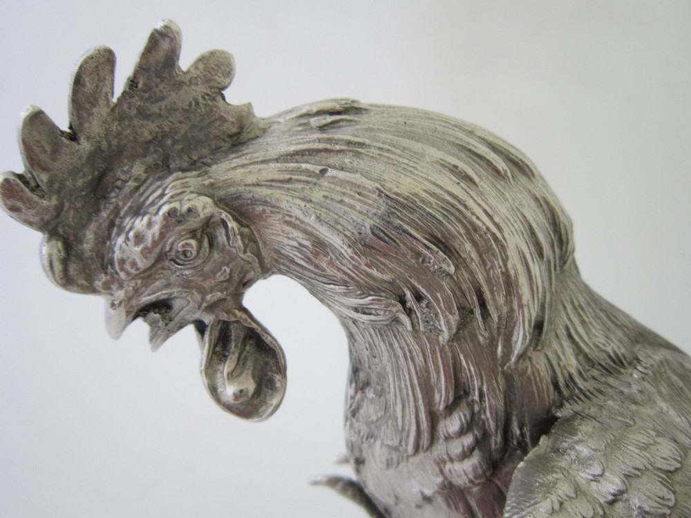 A pair of detailed sterling silver figures depicting fighting cockerels with open wings and realistic feather textures. View XII