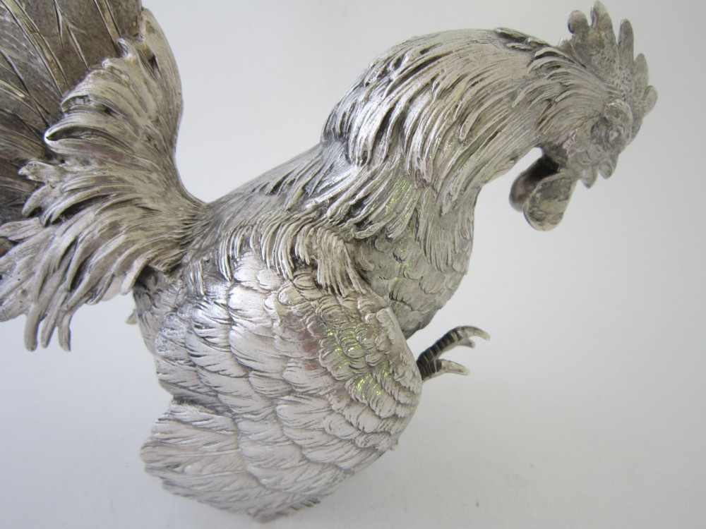 A pair of detailed sterling silver figures depicting fighting cockerels with open wings and realistic feather textures. View XIII