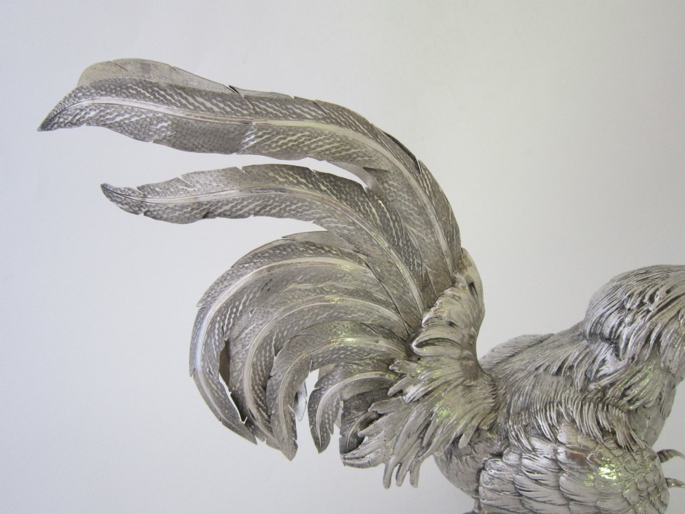 A pair of detailed sterling silver figures depicting fighting cockerels with open wings and realistic feather textures. View XV