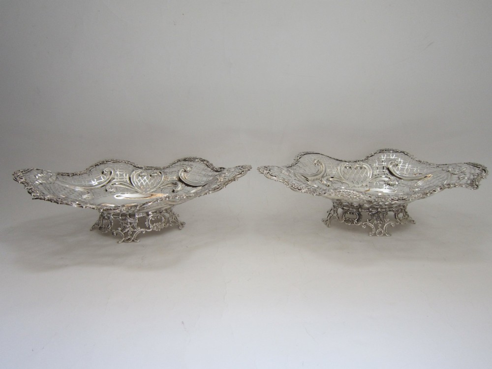 A pair of late Victorian sterling silver dishes featuring intricate pierced lattice pattern, ornate scroll borders, and raised feet. View II