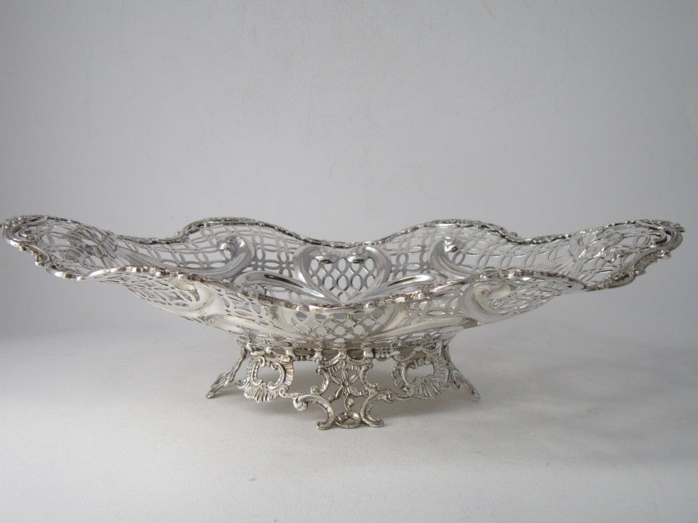 A pair of late Victorian sterling silver dishes featuring intricate pierced lattice pattern, ornate scroll borders, and raised feet. View III