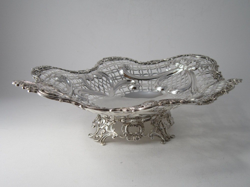A pair of late Victorian sterling silver dishes featuring intricate pierced lattice pattern, ornate scroll borders, and raised feet. View V
