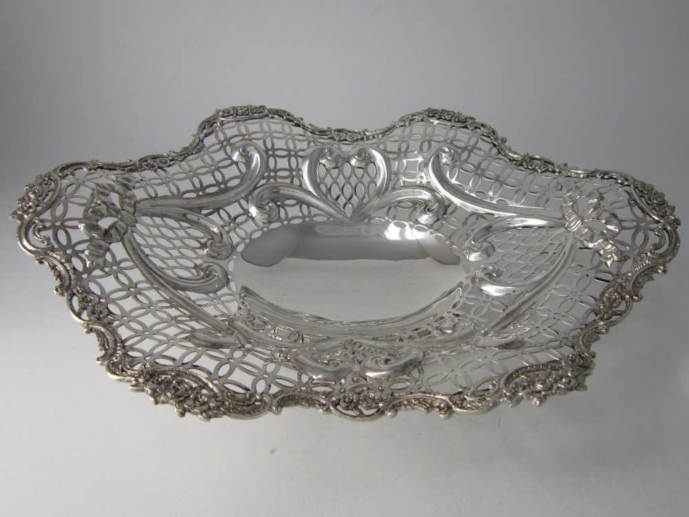 A pair of late Victorian sterling silver dishes featuring intricate pierced lattice pattern, ornate scroll borders, and raised feet. View VI