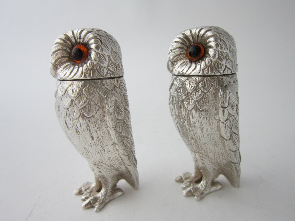 A pair of cast sterling silver salt and pepper shakers in the form of standing owls with textured feather detailing and dark amber glass eyes. View II