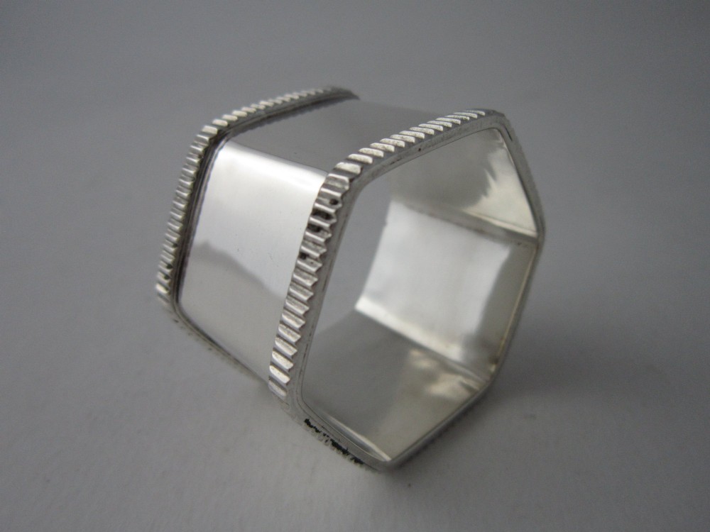 An octagonal sterling silver napkin ring with reeded borders presented inside a fitted blue velvet case. View III