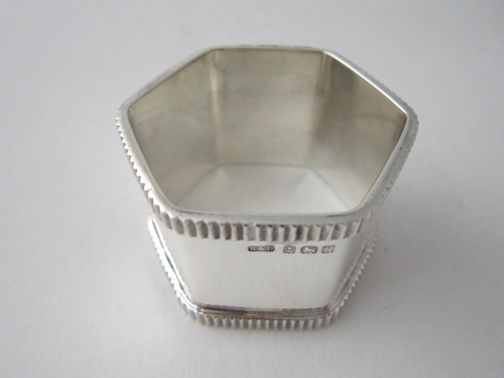 An octagonal sterling silver napkin ring with reeded borders presented inside a fitted blue velvet case. View IV