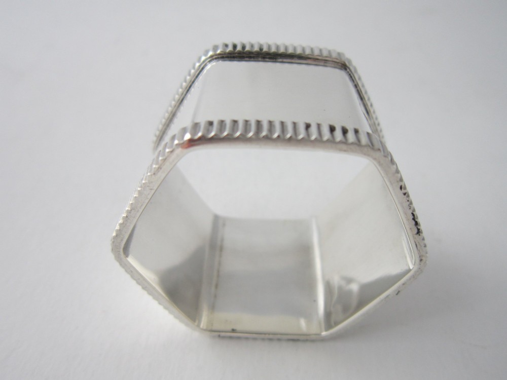 An octagonal sterling silver napkin ring with reeded borders presented inside a fitted blue velvet case. View V