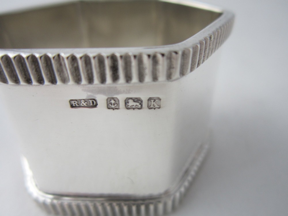 An octagonal sterling silver napkin ring with reeded borders presented inside a fitted blue velvet case. View VI
