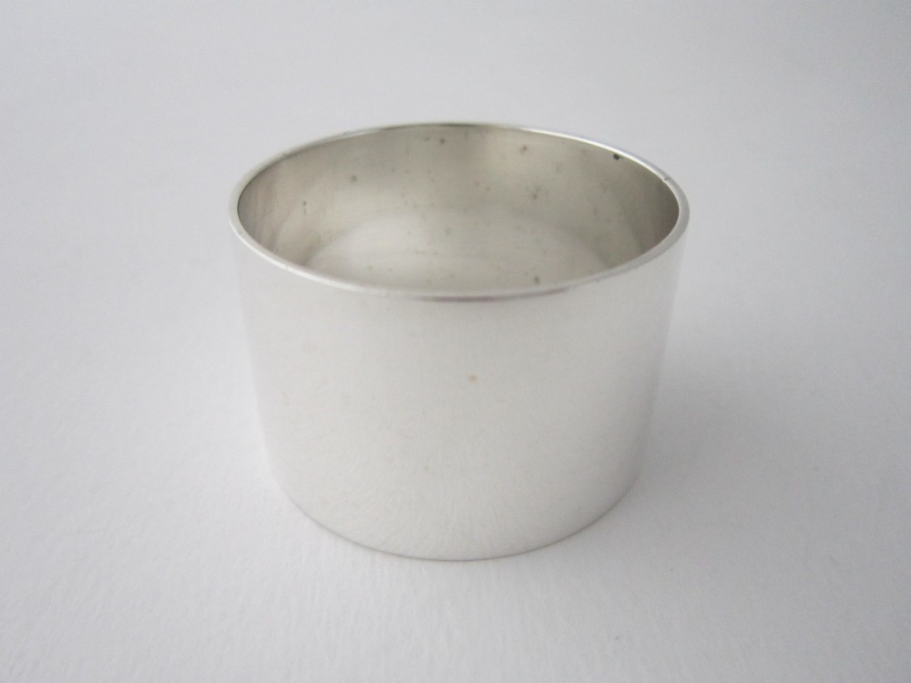 A plain cylindrical sterling silver napkin ring displaying a polished metallic finish.