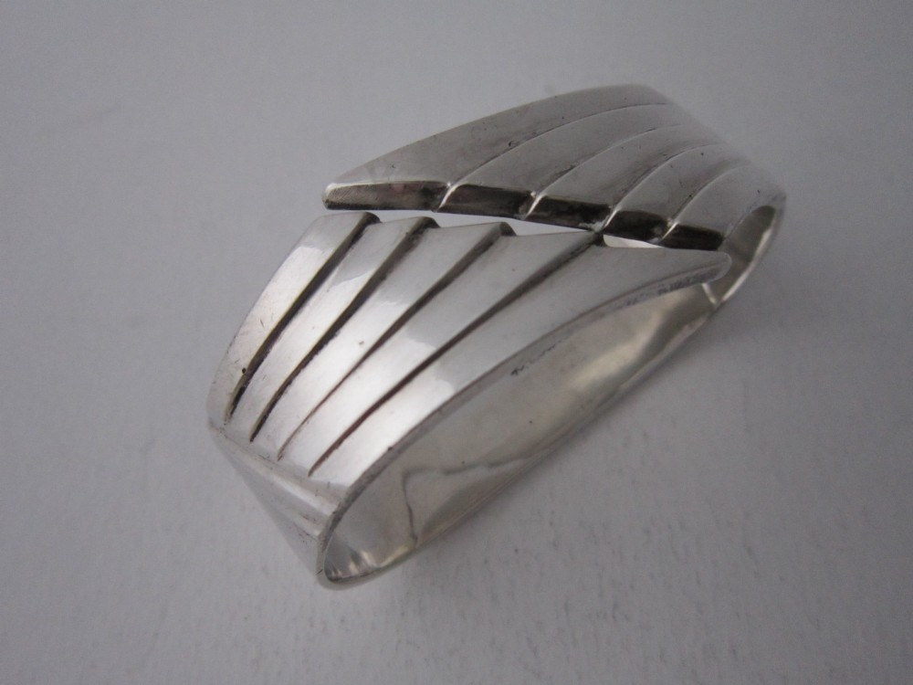 A sterling silver napkin ring crafted in 1949 with an asymmetrical geometric motif featuring grooved stepped lines.