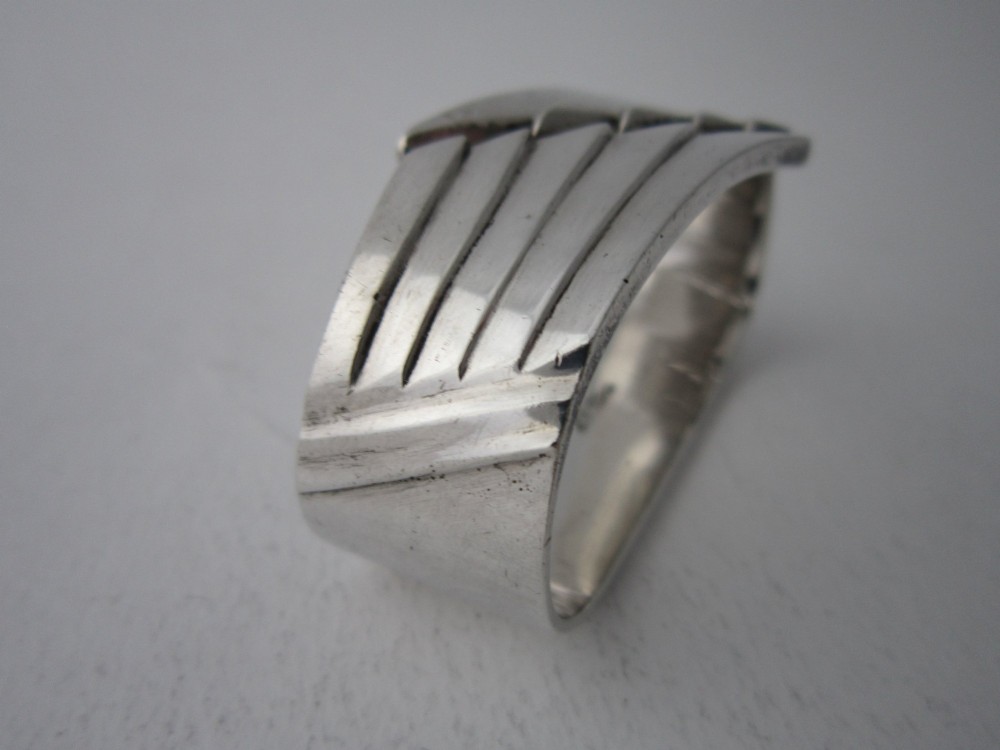 A sterling silver napkin ring crafted in 1949 with an asymmetrical geometric motif featuring grooved stepped lines. View III