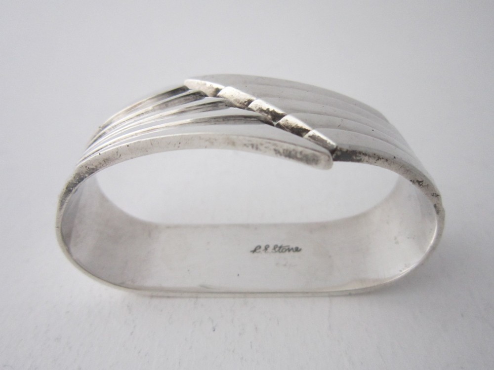 A sterling silver napkin ring crafted in 1949 with an asymmetrical geometric motif featuring grooved stepped lines. View IV