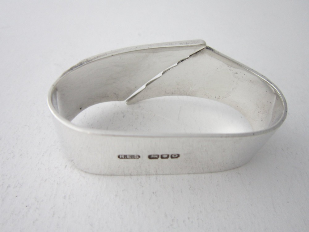 A sterling silver napkin ring crafted in 1949 with an asymmetrical geometric motif featuring grooved stepped lines. View V