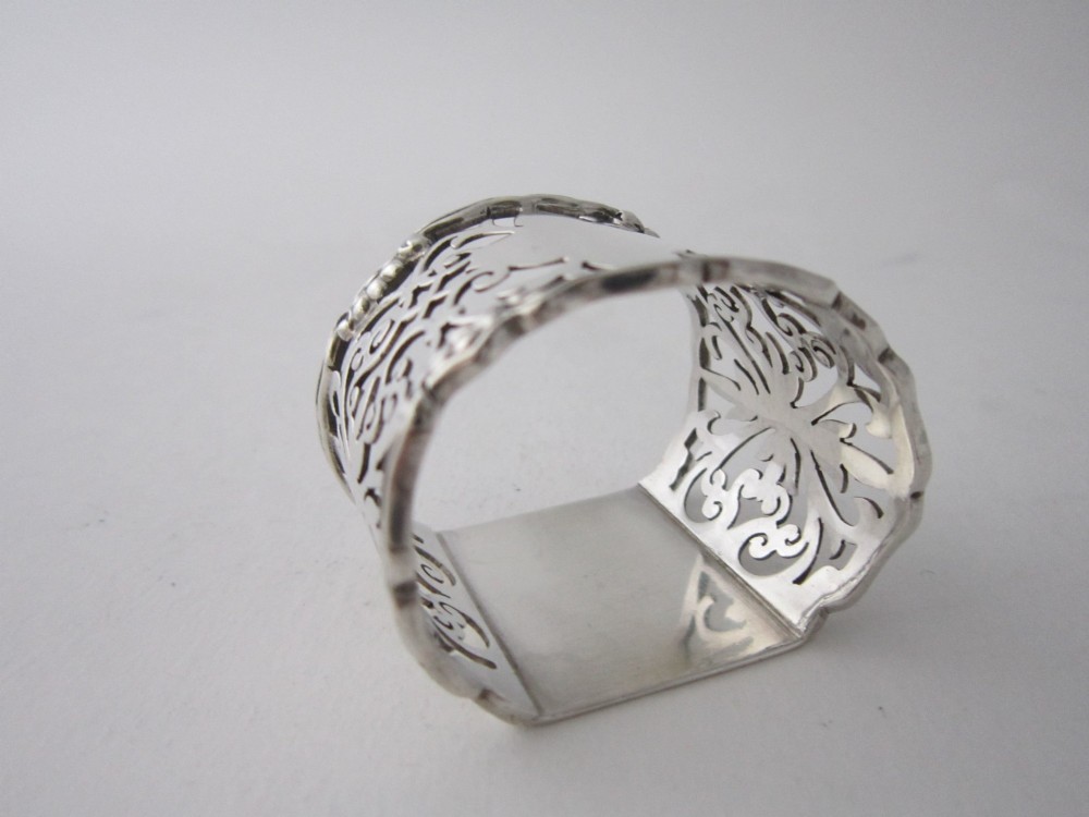 An antique George V sterling silver napkin ring featuring intricate pierced scrollwork and a blank central cartouche. View IV