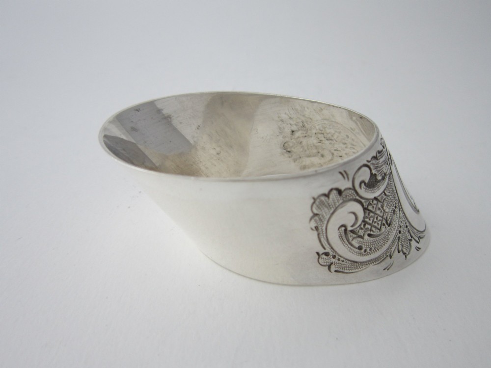A Victorian sterling silver napkin ring featuring intricate foliate scroll engraving and visible British hallmarks on a reflective curved surface. View IV