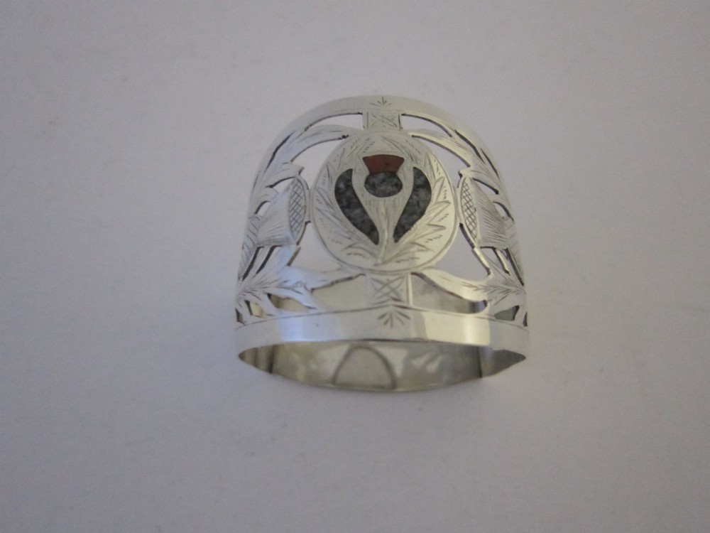 A pierced sterling silver napkin ring featuring engraved Scottish thistle motifs and a central inlaid agate stone.
