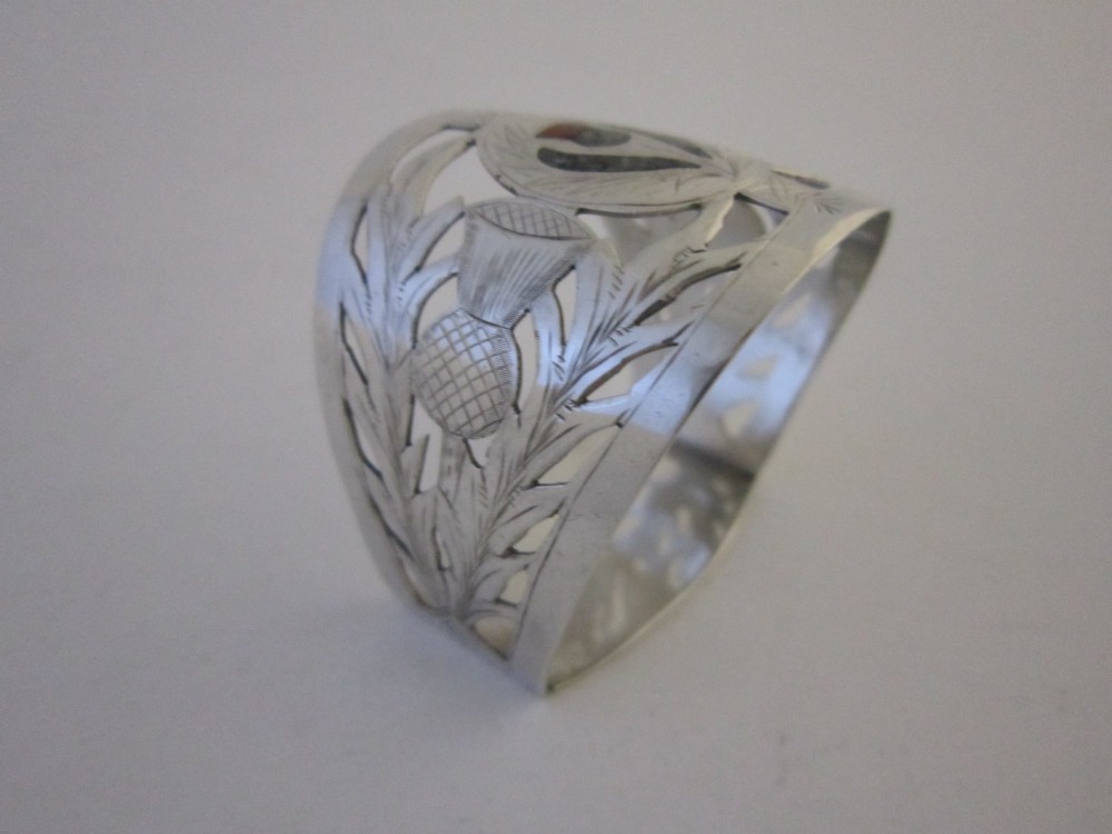 A pierced sterling silver napkin ring featuring engraved Scottish thistle motifs and a central inlaid agate stone. View III