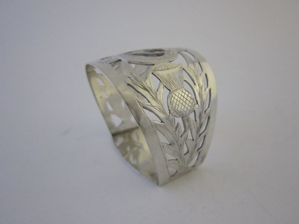 A pierced sterling silver napkin ring featuring engraved Scottish thistle motifs and a central inlaid agate stone. View IV