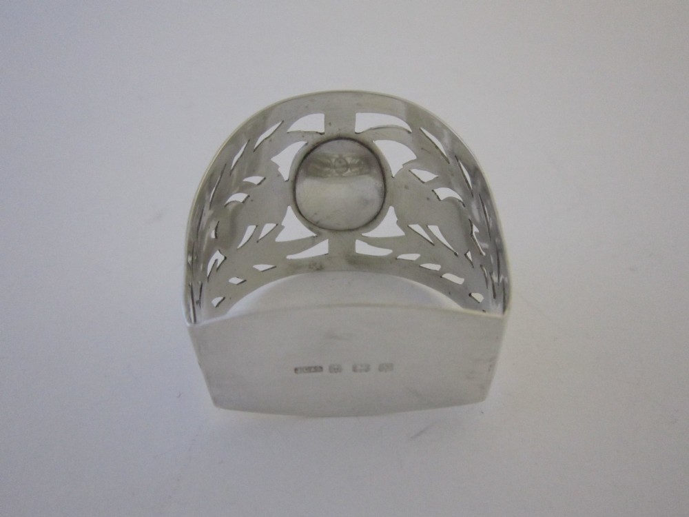 A pierced sterling silver napkin ring featuring engraved Scottish thistle motifs and a central inlaid agate stone. View V
