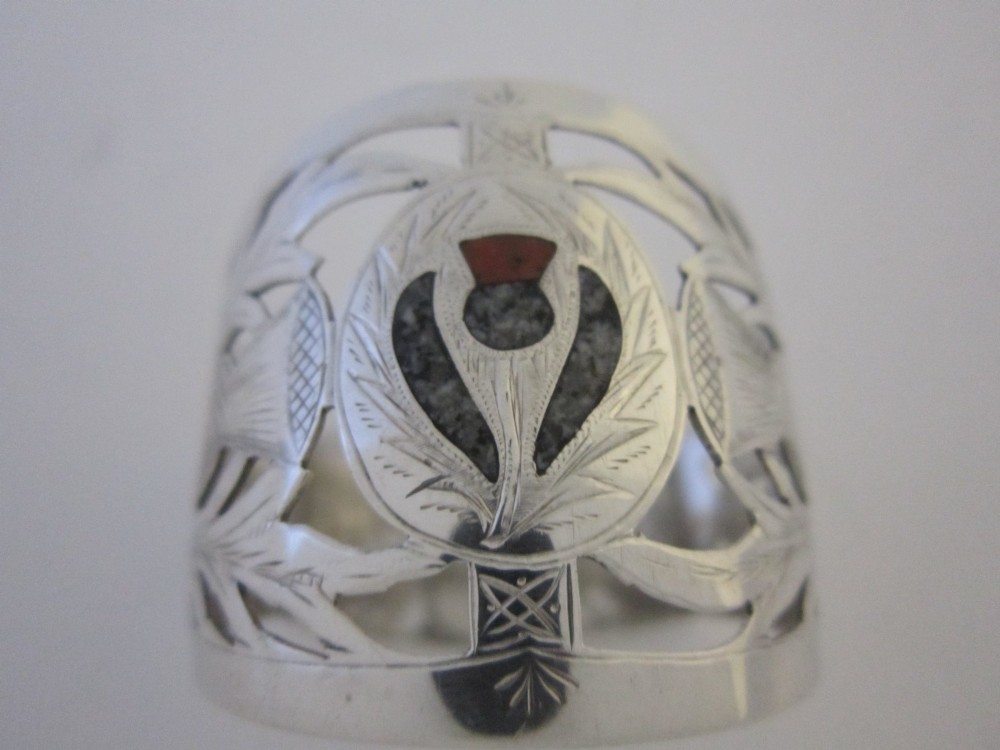 A pierced sterling silver napkin ring featuring engraved Scottish thistle motifs and a central inlaid agate stone. View VI