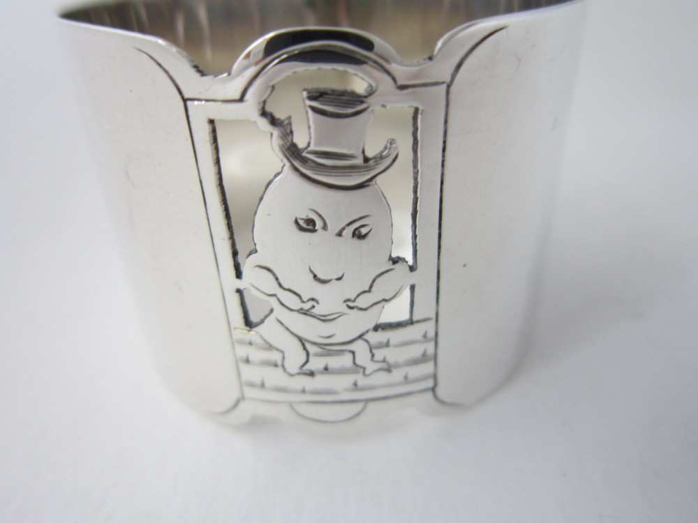 A sterling silver napkin ring featuring a pierced cutout motif of Humpty Dumpty wearing a top hat. View VI