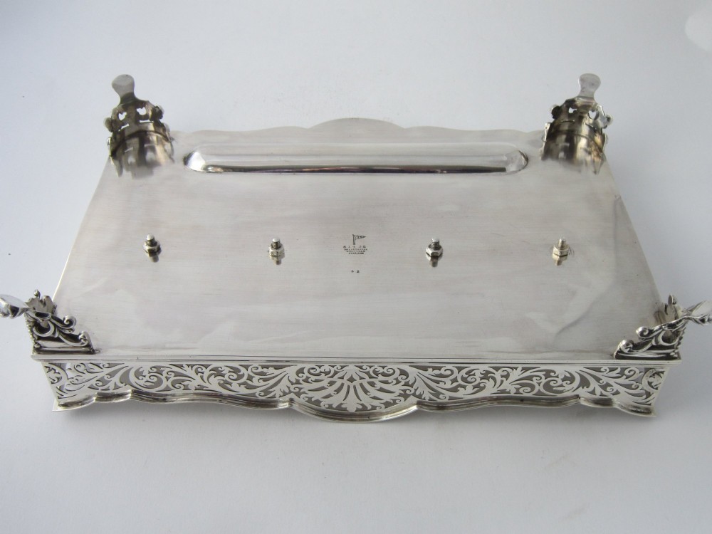 A George V sterling silver tray featuring a pierced gallery, scroll feet, a central pen recess, and two square cut-glass inkwells with silver lids. View V