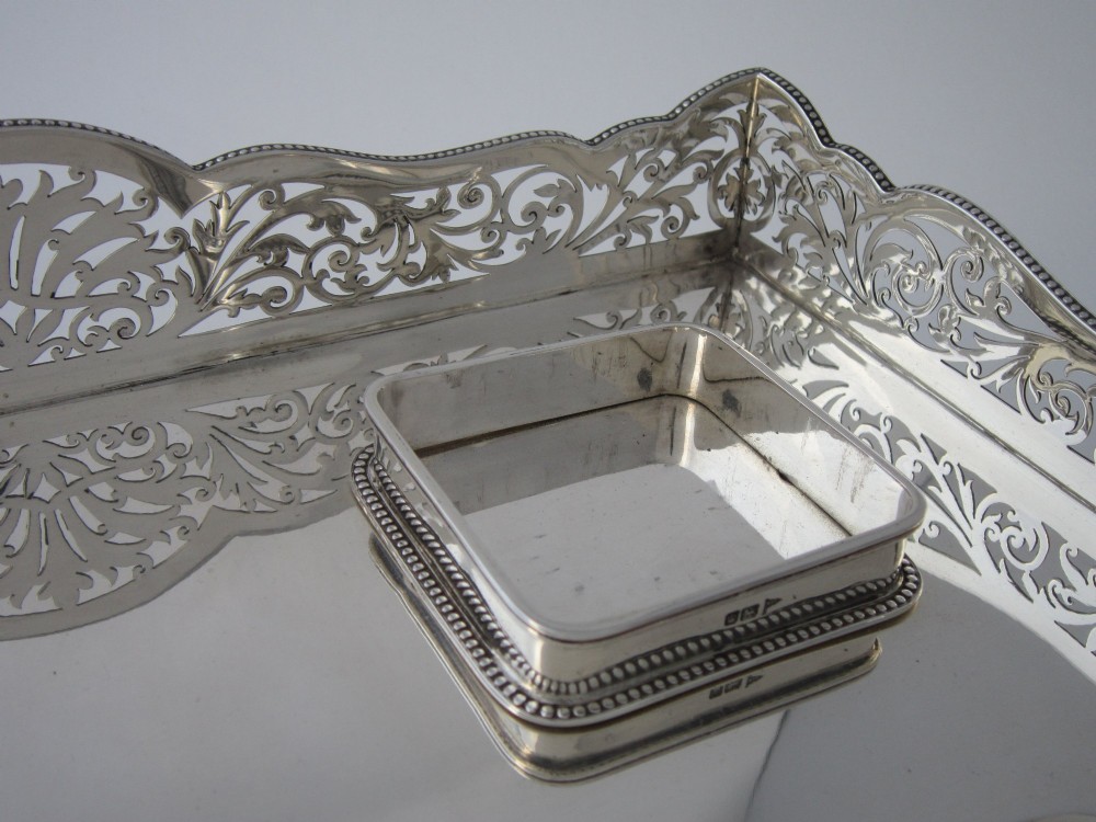 A George V sterling silver tray featuring a pierced gallery, scroll feet, a central pen recess, and two square cut-glass inkwells with silver lids. View VI