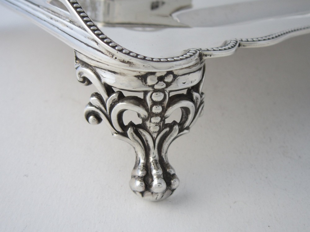 A George V sterling silver tray featuring a pierced gallery, scroll feet, a central pen recess, and two square cut-glass inkwells with silver lids. View VII