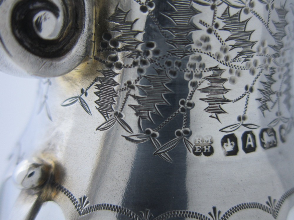 A Victorian clear glass claret jug with an engraved sterling silver collar, hinged lid with finial, and an ornate scroll handle. View VII