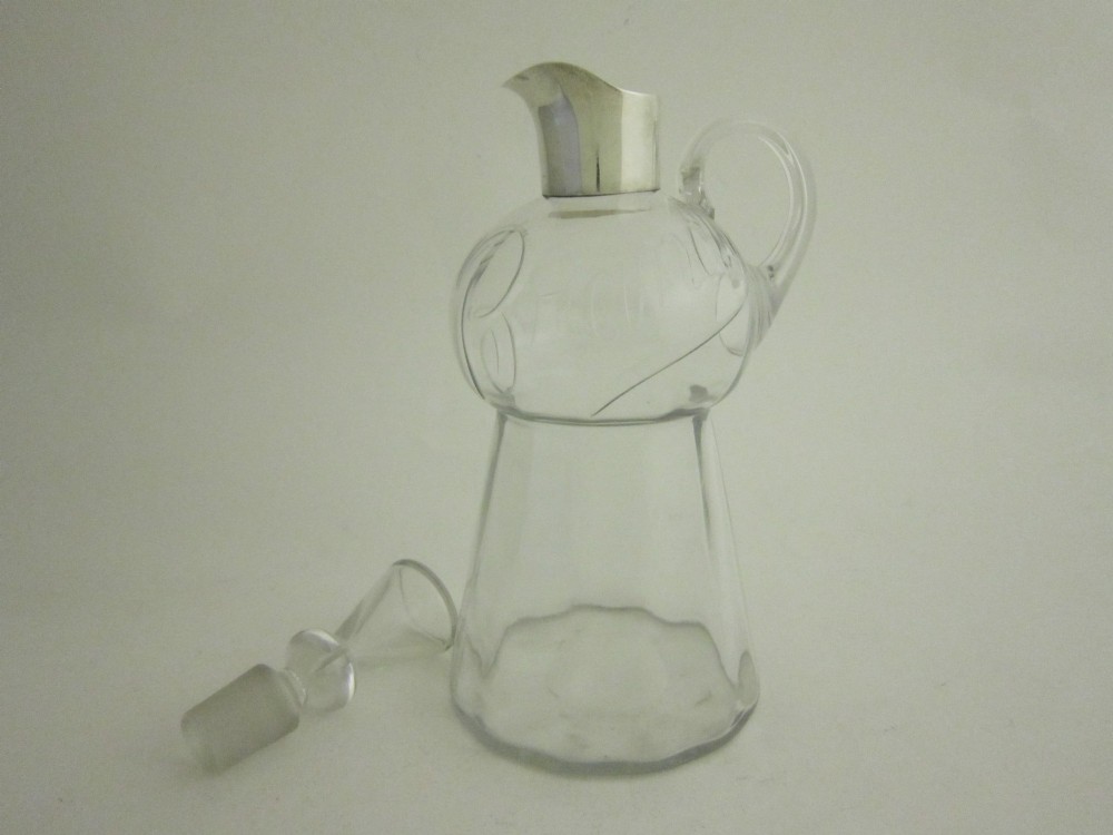 Clear glass brandy decanter with a sterling silver collar spout, a single side loop handle, and a geometric glass stopper. View II