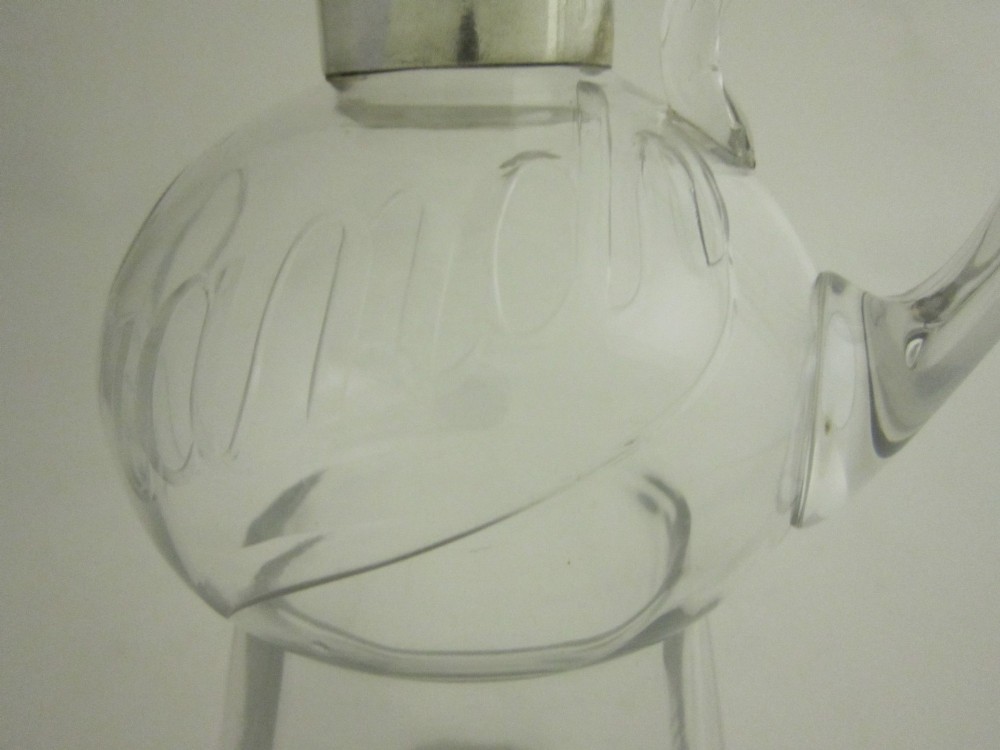 Clear glass brandy decanter with a sterling silver collar spout, a single side loop handle, and a geometric glass stopper. View V