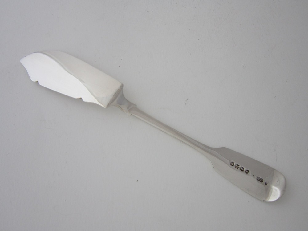 An antique Victorian sterling silver butter knife featuring a classic Fiddle pattern handle and a shaped spreading blade. View IV