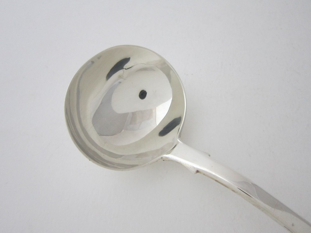 A Victorian sterling silver sauce ladle featuring a fiddle pattern handle and a round deep bowl, displayed on a plain white surface. View II
